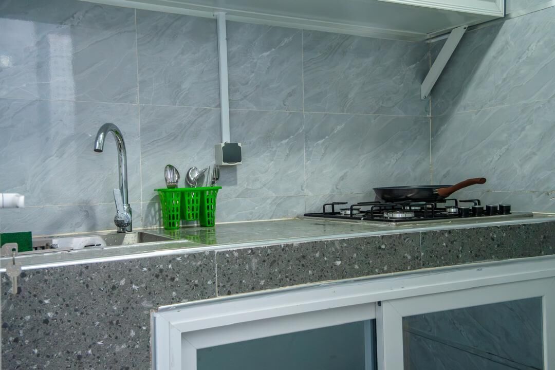 A kitchen with a sink, faucet, green basket, stove, and marble backsplash.