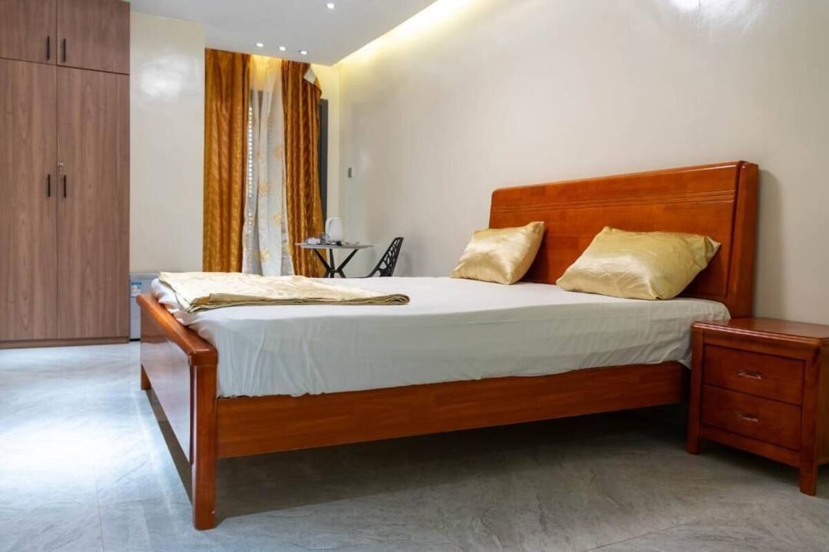 A bedroom with a wooden bed, a nightstand, a wardrobe, and a small table with a chair.