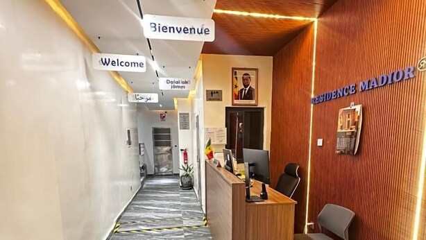 En hotellobby med ett marmorgolv, en receptionsdisk i trä och en skylt med texten ”Välkommen”.