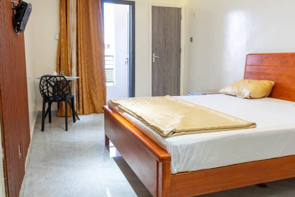 A bedroom with a wooden bed, a small table with a chair, and a door.