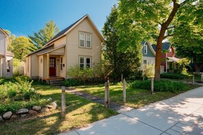 Einbungalow mit Veranda, einer roten Tür und einem kleinen Vorgarten mit einem Weg zum Haus.