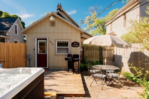 Een gezellig buitenterras met een jacuzzi, een barbecue en een eettafel met stoelen.