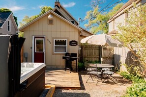 Een gezellige achtertuin met een hottub, een barbecue en een patio met stoelen.
