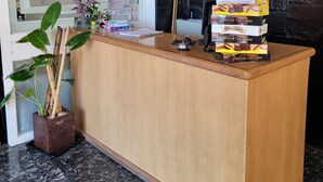 A reception desk with a computer, a plant, and a menu board. - El Mirador (Villa Carlos Paz)