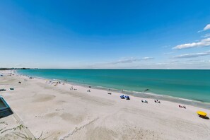 Ein Strand mit klarem türkisblauem Wasser und Sandstrand, ausgestattet mit Sonnenschirmen.