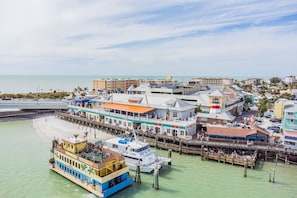 Ein Hotel direkt am Wasser mit einer Anlegestelle, einem Boot, das an der Anlegestelle festgemacht ist, und Blick auf Strand und Meer.