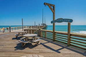 Eine Holzsteg mit Picknicktischen und einem Schild, auf dem 'Jennette's Pier' steht.