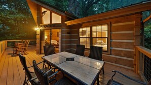 Una baita di legno con veranda, tavolo e sedie.