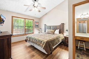 A bedroom with a bed, a desk, a chair, a ceiling fan, a window with blinds, and a mirror. - Cedar Ridge Haven | Hot Tub, Fireplace & More! (Gatlinburg)