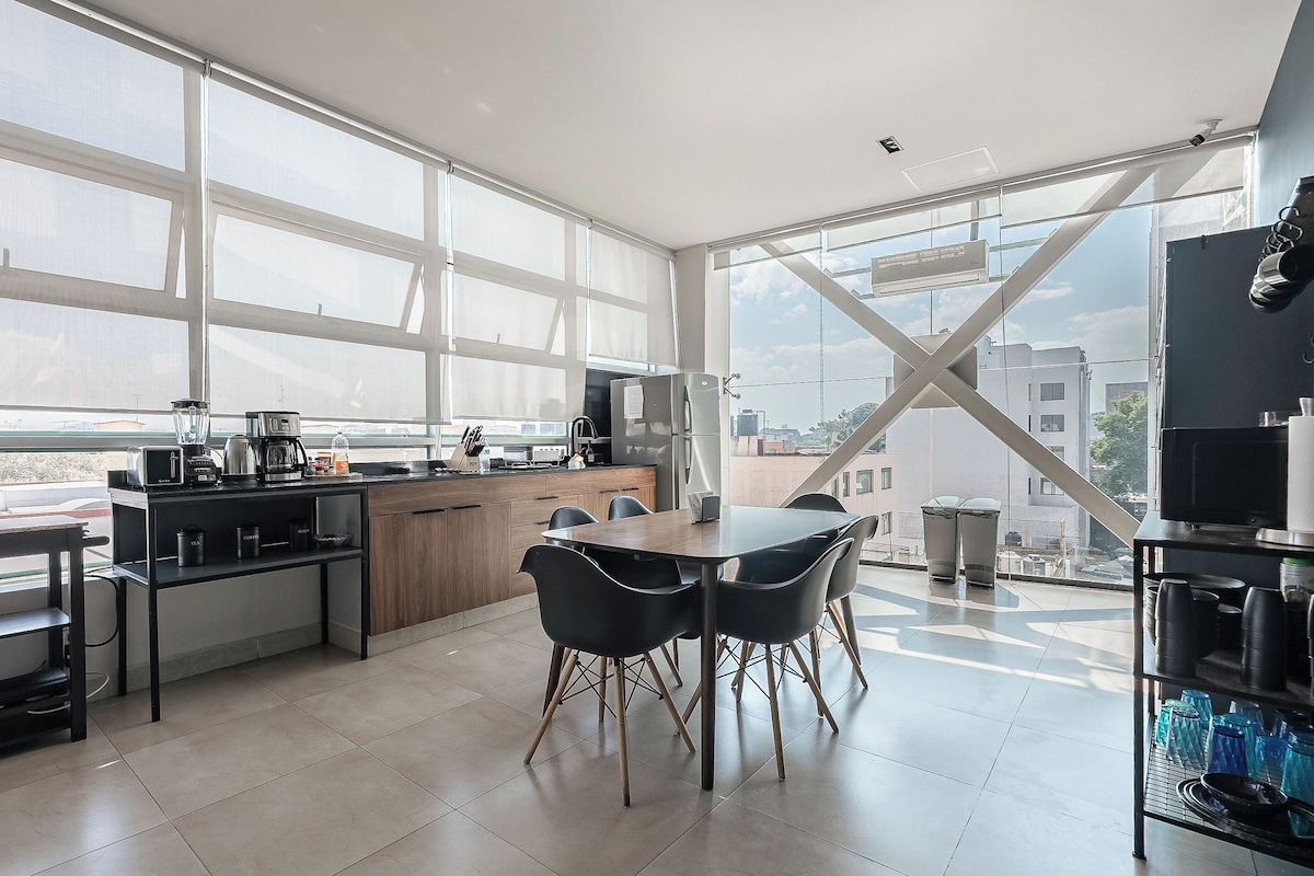 Una cocina moderna con ventanas amplias, un comedor con sillas y vistas a la ciudad.