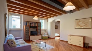A living room with a sofa, a TV, a bookshelf, and a painting on the wall. - CORTE BARBIERI (Ceraino)