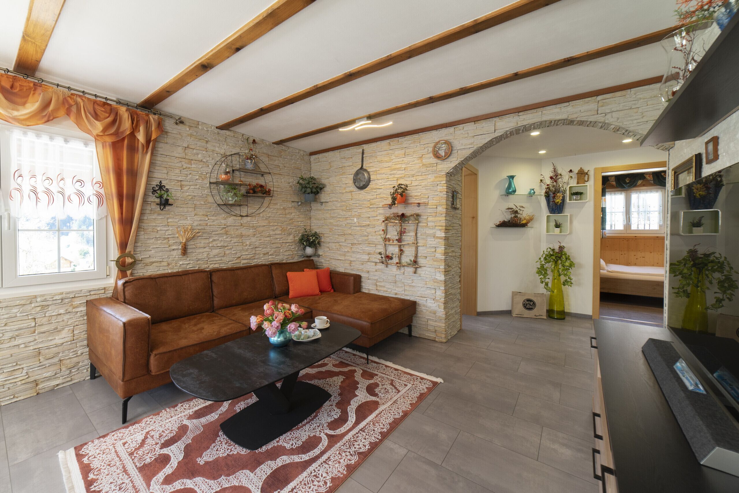 A bright living room with a corner sofa and a decorative stone wall