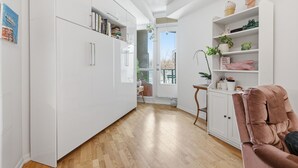 A modern kitchen with white cabinets, a wooden floor, and a pink chair.