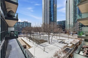 A modern high-rise building with multiple balconies, a snow-covered courtyard, and a clear sky. - Downtown Bachelor Steps to Transit, Dining & Nightlife (Toronto)