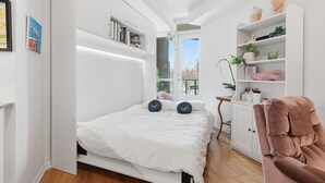 A bedroom with a bed, white shelving, a desk, and a chair.