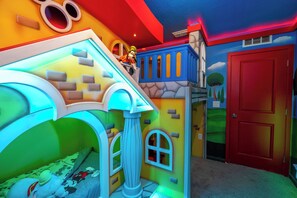 Ein Spielzimmer mit einem Bett, einem Spielhäuschen und einer roten Tür.