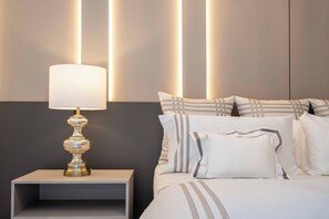 Ein ordentlich gemachtes Bett mit gestreifter Bettwäsche, eine Nachttischlampe und ein kleiner Nachttisch.