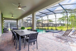 Eine überdachte Terrasse mit Pool, Sitzgelegenheiten im Freien und Blick auf die Umgebung.