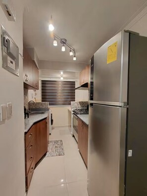 Een moderne keuken met roestvrijstalen apparatuur, houten kastjes en een betegelde achterwand.
