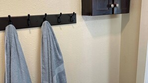 Un baño con un perchero con dos toallas, un mueble de madera oscura y una pared con textura.