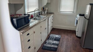 Una cocina compacta con armarios blancos, un lavamanos, una estufa y un refrigerador.