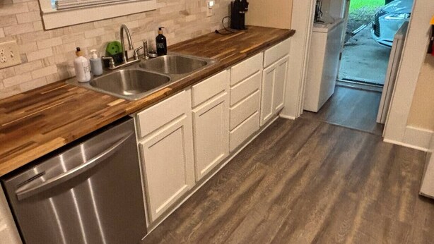 Eine Küche mit Holzausziehtisch, Spüle aus Edelstahl und weißen Schränken.
