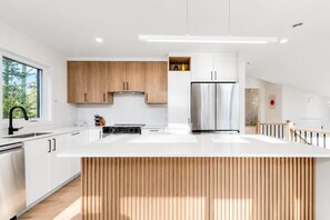 Eine moderne Küche mit weißen Schränken, einem Edelstahlkühlschrank und einer Holztischinsel.