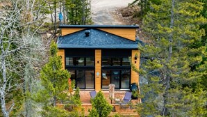 Ein modernes Lodge mit einer großen Terrasse, umgeben von Bäumen.