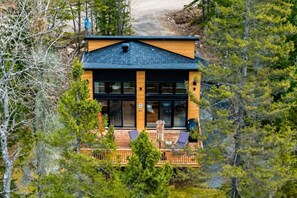 Ein modernes Lodge mit einer großen Terrasse, umgeben von Bäumen.