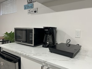 Eine Küche mit Mikrowelle, Kaffeemaschine und einer Pflanze.
