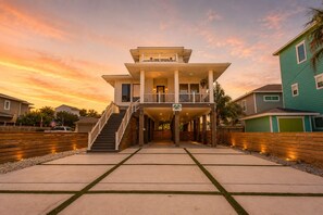 A two-story house with a balcony, a staircase, and a driveway. - SE907 4BD, 4.5BA, Private Heated Pool, Pickleball Court, Parking for 5 (Port Aransas)