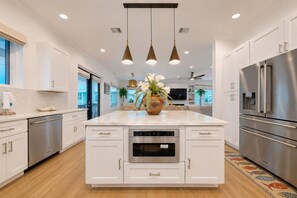 A modern kitchen with white cabinetry, stainless steel appliances, and pendant lighting. - SE907 4BD, 4.5BA, Private Heated Pool, Pickleball Court, Parking for 5 (Port Aransas)