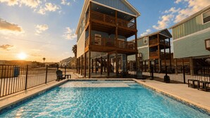 Una piscina con bordo in legno e un edificio a due piani con balconi.
