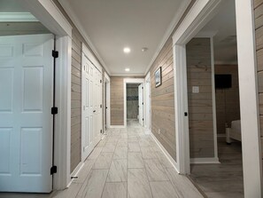 A hallway with wooden paneling, white doors, and a tiled floor. - CL9 Shared Pool, Charcoal Grill, Old Town Port A (Port Aransas)