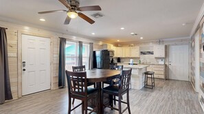 A kitchen with a dining table, chairs, a ceiling fan, and wooden flooring. - ACC8 Shared Pool, Pet Friendly, In Town (Port Aransas)