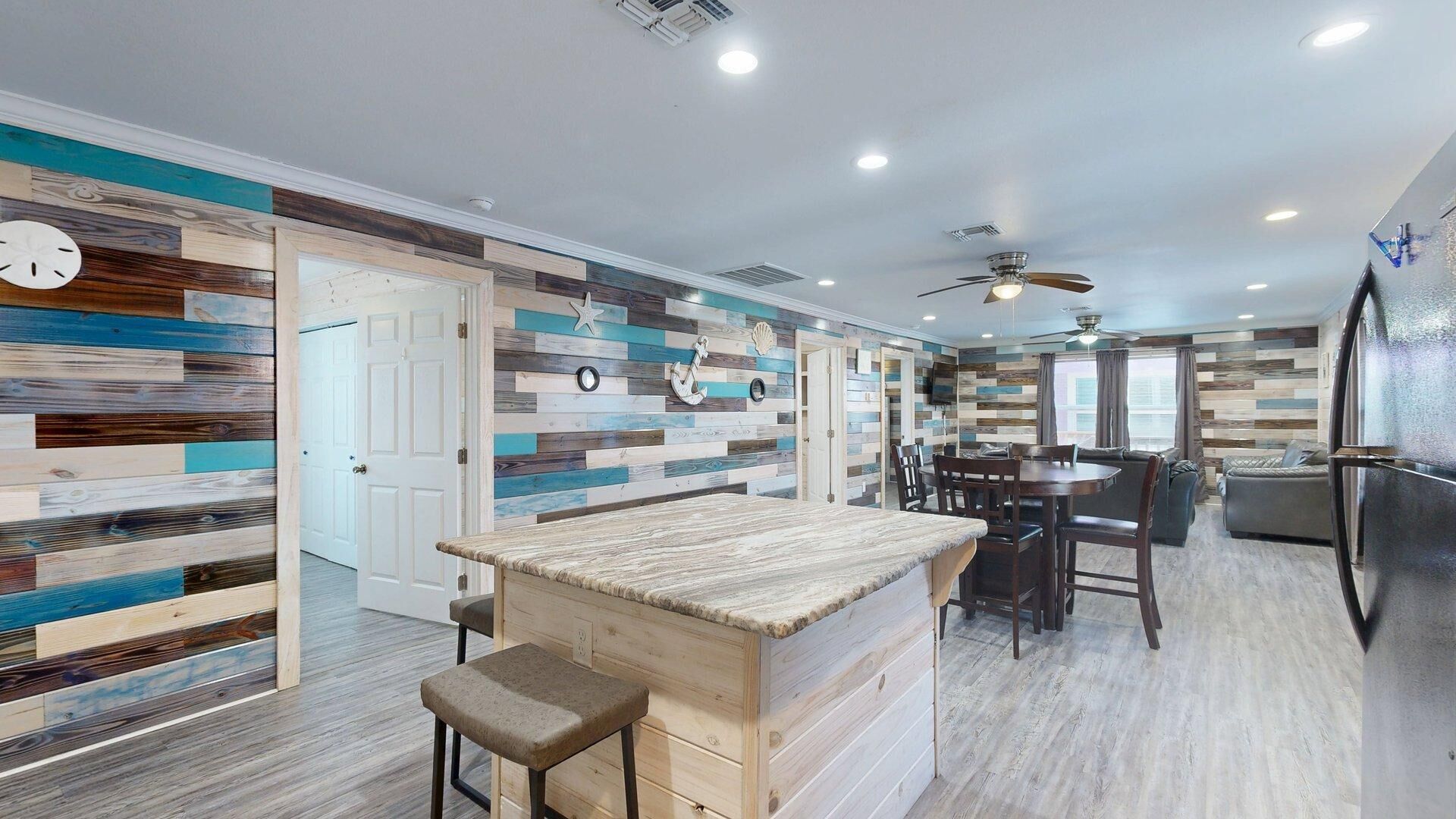 A modern kitchen with a wooden island, a dining area with a round table, and a living room with a sofa and a TV.