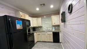A kitchen with light wooden cabinets, a black refrigerator, a microwave, a sink, and a dishwasher. - ACC9 Shared Pool, Pet Friendly, In Town (Port Aransas)