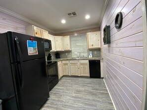 A kitchen with light wooden cabinets, a black refrigerator, a microwave, a sink, and a dishwasher. - ACC9 Shared Pool, Pet Friendly, In Town (Port Aransas)