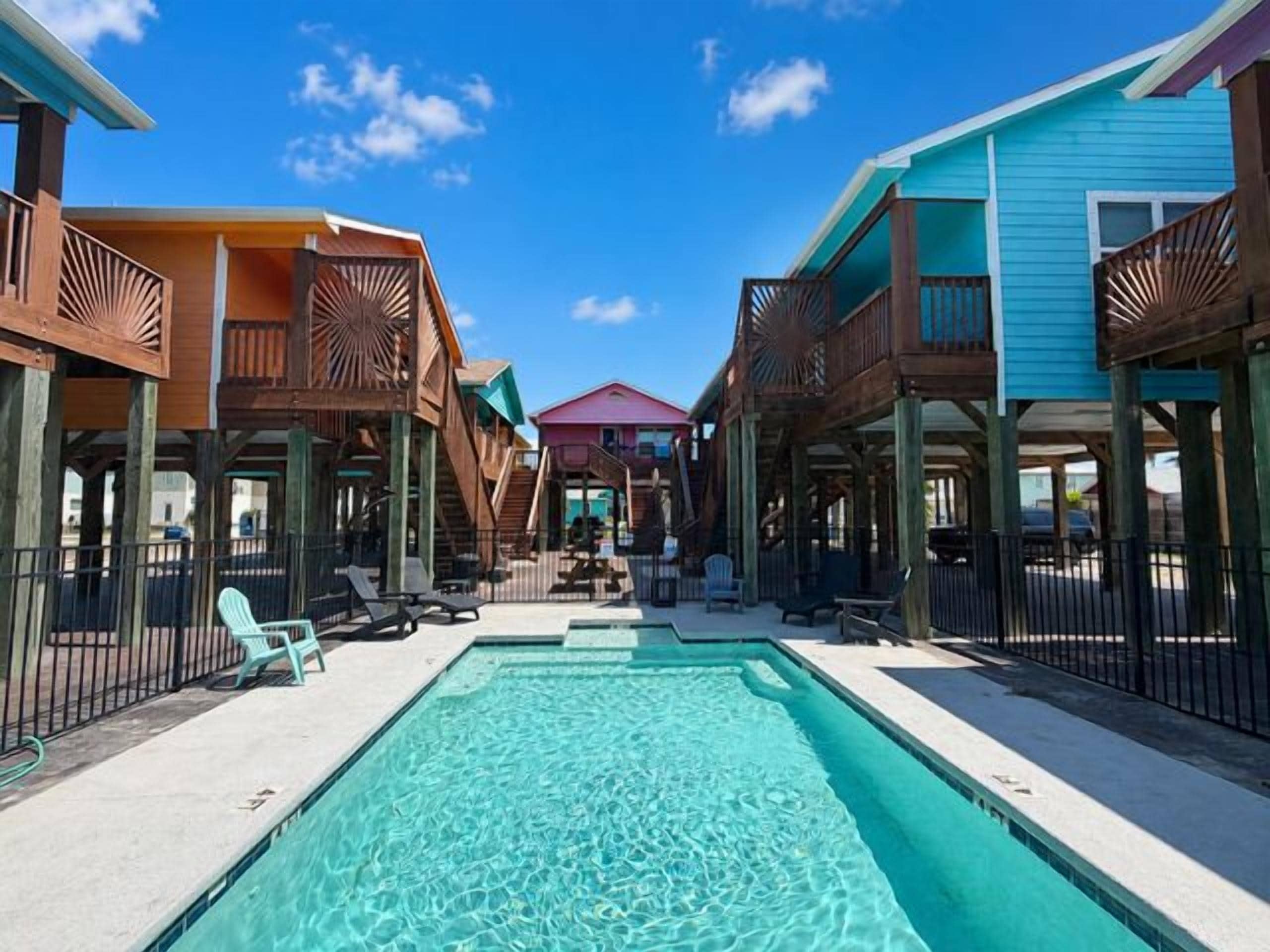 Un espace piscine doté de terrasses en bois, de chaises longues et d’une piscine à l’eau d’un bleu cristallin.