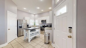 A modern kitchen with white cabinetry, stainless steel appliances, and a tiled floor. - FH6, Near Beach, Shared Pool, Pet Friendly, Charcoal Grill (Port Aransas)