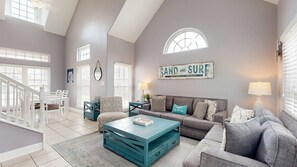 A spacious living room with a high ceiling, a staircase, and a large window. - FH6, Near Beach, Shared Pool, Pet Friendly, Charcoal Grill (Port Aransas)
