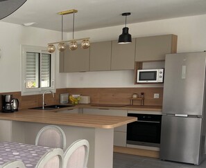 A modern kitchen with a central island, stainless steel appliances, and a wooden countertop. - Family home for young & old, near the sea (Plouescat)