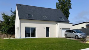 Ein modernes, zweigeschossiges Haus mit Garage, Auffahrt und gepflegtem Rasen.