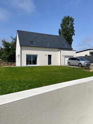 A modern two-story house with a garage, a driveway, and a well-maintained lawn. - Family home for young & old, near the sea (Plouescat)