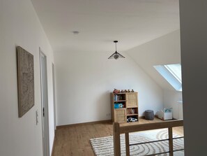 A room with a sloped ceiling, a wooden bookshelf, a small table, and a window. - Family home for young & old, near the sea (Plouescat)