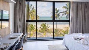 Une chambre d’hôtel avec une grande fenêtre, un lit, un bureau avec une chaise et un téléviseur.