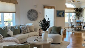 Una sala de estar amplia con un sofá, sillones, una mesa de centro y un comedor con mesa y sillas.