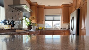 Una cocina con armarios de madera, un refrigerador de acero inoxidable y una encimera de granito.