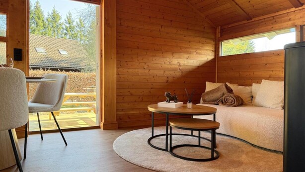 A cozy cabin interior with a round table, a sofa, and a chair. - Peace, Comfort & Nature at This Home (Durbuy)