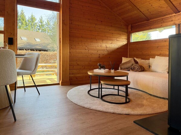 A cozy cabin interior with a round table, a sofa, and a chair. - Peace, Comfort & Nature at This Home (Durbuy)